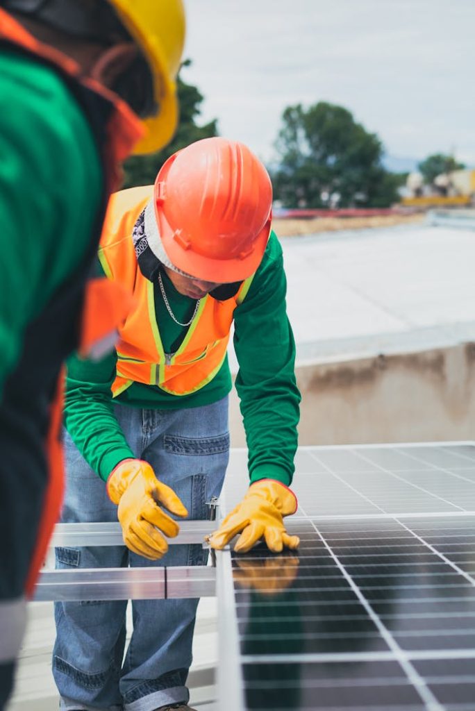 pexels-photo-8853507 Worker in safety gear installing solar panels on a rooftop.
